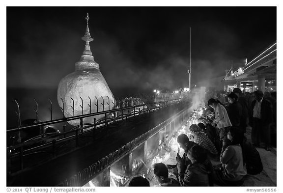 Pilgrims pray with candles behind the Golden Rock. Kyaiktiyo, Myanmar (black and white)