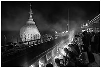 Pilgrims pray with candles behind the Golden Rock. Kyaiktiyo, Myanmar ( black and white)