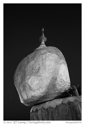 Pilgrims affix golden leaves to balancing boulder stupa at dawn. Kyaiktiyo, Myanmar (black and white)