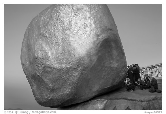 Monks praying at the Golden Rock balancing boulder. Kyaiktiyo, Myanmar (black and white)