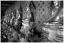 Monks sitting below row of buddha images, Wat Arun. Bangkok, Thailand (black and white)