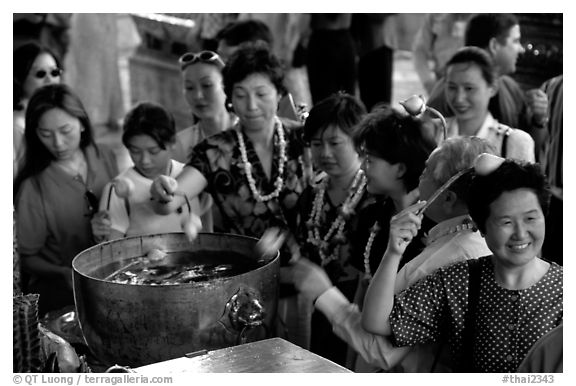 Worshippers dip lotus flowers and bring them to their heads. Bangkok, Thailand (black and white)