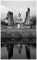 Buddha image reflected in moat, morning, Wat Mahathat. Sukothai, Thailand (black and white)