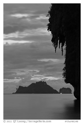 Limestone crag with stalactite, distant islet, boat light, Railay. Krabi Province, Thailand (black and white)