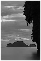 Limestone crag with stalactite, distant islet, boat light, Railay. Krabi Province, Thailand (black and white)