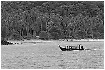 Longtail boat sailing in front of palm-fringed beach, Phi-Phi island. Krabi Province, Thailand ( black and white)