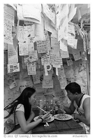 Couple eating Pad Thai below notes of praise left by customers, Ko Phi Phi. Krabi Province, Thailand (black and white)