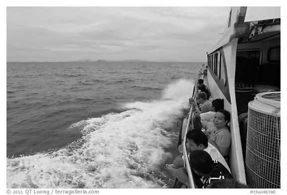 Passengers sitting on side of boat. Krabi Province, Thailand (black and white)