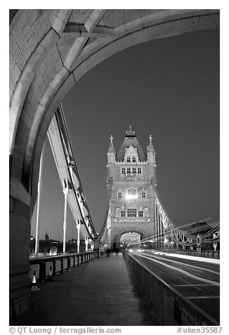 Walkway and road traffic on the Tower Bridge at night. London, England, United Kingdom (black and white)