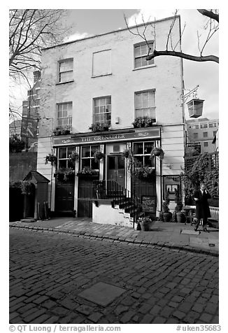 Cobblestone mews, pub, and man standing outside. London, England, United Kingdom