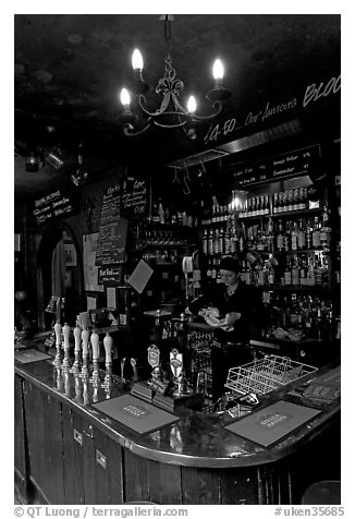 Woman cleaning glass at the bar, pub The Grenadier. London, England, United Kingdom