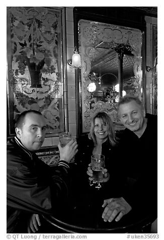 Friends cheering up with a beer in front of echted glass and fine tiles of pub Princess Louise. London, England, United Kingdom