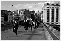 Office workers pouring out of the city of London across London Bridge, late afternoon. London, England, United Kingdom (black and white)