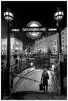 Woman with shopping bag entering subway at night, Piccadilly Circus. London, England, United Kingdom (black and white)