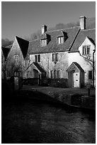 Cotswold type cottages and Bybrook River, Castle Combe. Wiltshire, England, United Kingdom (black and white)