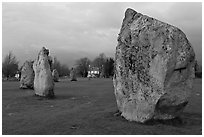 Standing stone circle and village house at dusk, Avebury, Wiltshire. England, United Kingdom ( black and white)