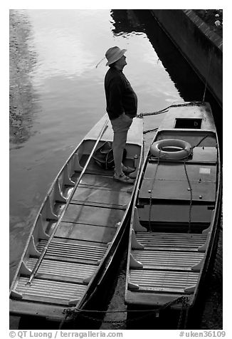Man standing in a rowboat, old town moat. Canterbury,  Kent, England, United Kingdom (black and white)