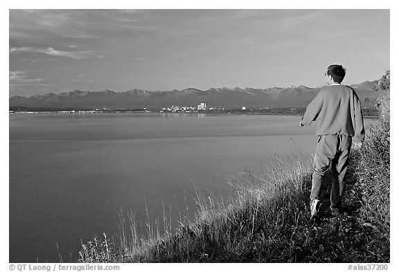 Man walking on the edge of Knik Arm in Earthquake Park, sunset. Anchorage, Alaska, USA (black and white)