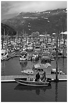 Small boat loaded at pier, harbor, and mountains. Whittier, Alaska, USA (black and white)