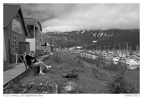 Couple sitting on bench by the harbor. Whittier, Alaska, USA