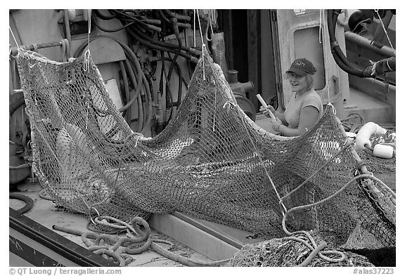 Woman repairing net on fishing boat. Whittier, Alaska, USA (black and white)