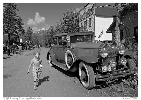 Girl on main street with red classic car. McCarthy, Alaska, USA (black and white)