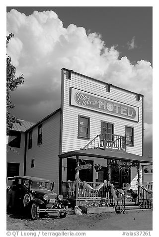 Ma Johnson hotel with classic car parked by, afternoon. McCarthy, Alaska, USA (black and white)