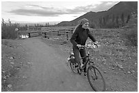 Woman on mountain bike with bridge behind. McCarthy, Alaska, USA ( black and white)