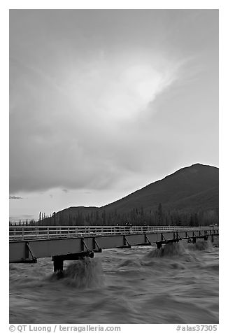 Footbridge with the Kennicott River swelled from the annual Hidden Lake flood. McCarthy, Alaska, USA (black and white)