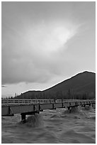 Footbridge with the Kennicott River swelled from the annual Hidden Lake flood. McCarthy, Alaska, USA (black and white)