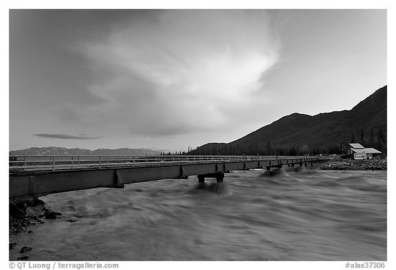 Kennicott River swelled from the Hidden Lake flood rushing against footbridge, sunset. McCarthy, Alaska, USA