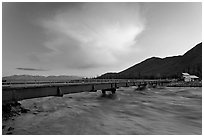 Kennicott River swelled from the Hidden Lake flood rushing against footbridge, sunset. McCarthy, Alaska, USA ( black and white)