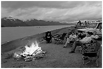 Sitting by campfire at midnight, waterfront campground. Seward, Alaska, USA (black and white)