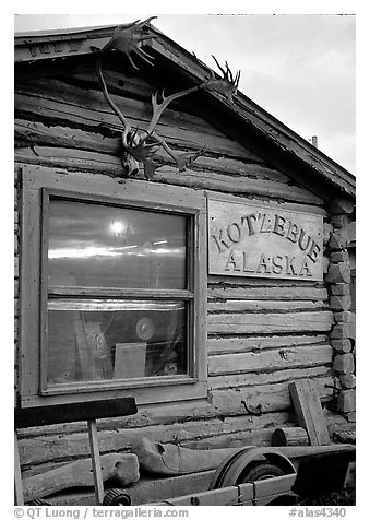 Log cabin with caribou antlers and sun reflected in window. Kotzebue, North Western Alaska, USA