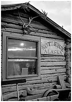 Log cabin with caribou antlers and sun reflected in window. Kotzebue, North Western Alaska, USA (black and white)