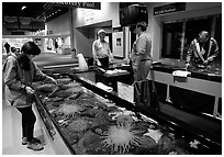 Tourist checks tidepool exhibit, Alaska Sealife center. Seward, Alaska, USA (black and white)