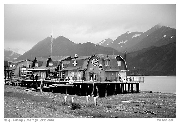 Stilt houses on the Spit, Kenai Mountains in the backgound. Homer, Alaska, USA (black and white)