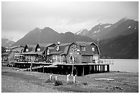 Stilt houses on the Spit, Kenai Mountains in the backgound. Homer, Alaska, USA ( black and white)