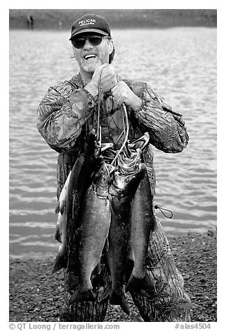 Man carrying salmon freshly caught in the Fishing Hole. Homer, Alaska, USA (black and white)