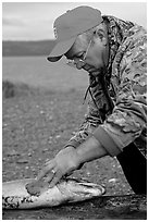 Fisherman preparing a salmon freshly caught in the Fishing Hole. Homer, Alaska, USA ( black and white)