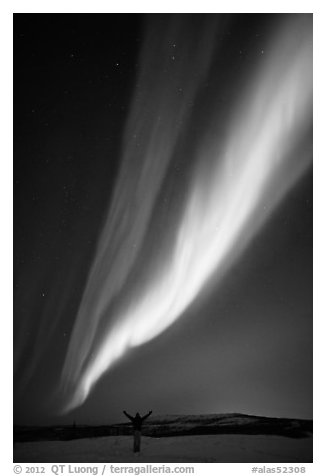 Aurora Borealis streaming above person with outstretched arms. Alaska, USA