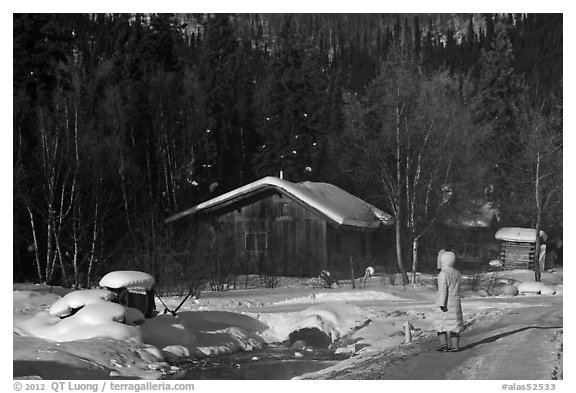 Woman with winter coat walking on path to cabins. Chena Hot Springs, Alaska, USA