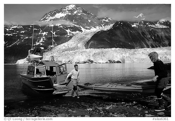 Kayakers unload  kayak from  water taxi boat at Black Sand Beach. Prince William Sound, Alaska, USA (black and white)