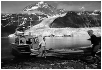 Kayakers unload  kayak from  water taxi boat at Black Sand Beach. Prince William Sound, Alaska, USA ( black and white)