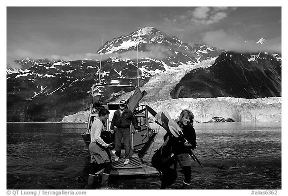 Kayakers unloading kayak from water taxi boat at Black Sand Beach. Prince William Sound, Alaska, USA