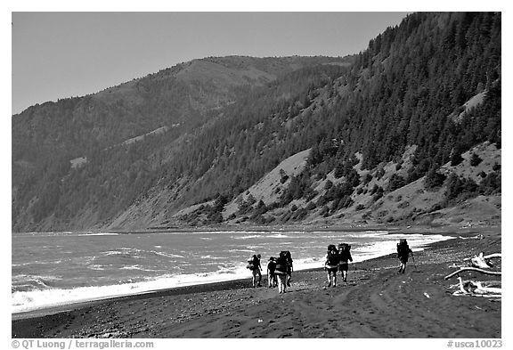 Backpackers on black sand beach and King Range, Lost Coast. California, USA (black and white)