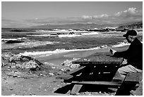Man reading on a picnic table, Bean Hollow State Beach. San Mateo County, California, USA ( black and white)