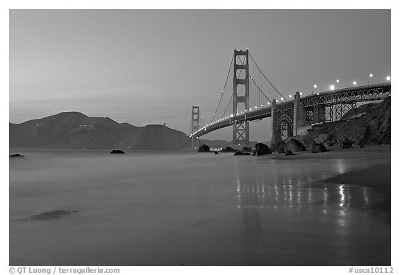 Golden Gage bridge at dusk, reflected in wet sand at East Baker Beach. San Francisco, California, USA (black and white)