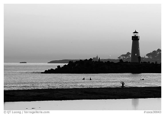 Lighthouse and Surfers in the water at sunset. Santa Cruz, California, USA (black and white)