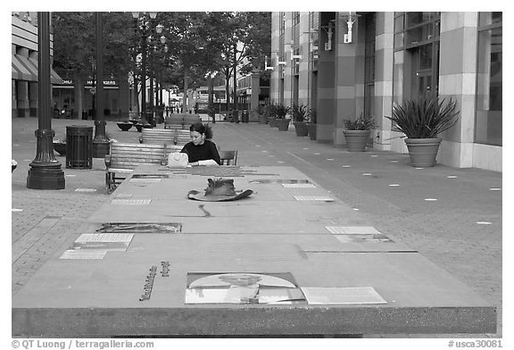 Woman sitting at a commemorative table in a downtown alley. San Jose, California, USA (black and white)